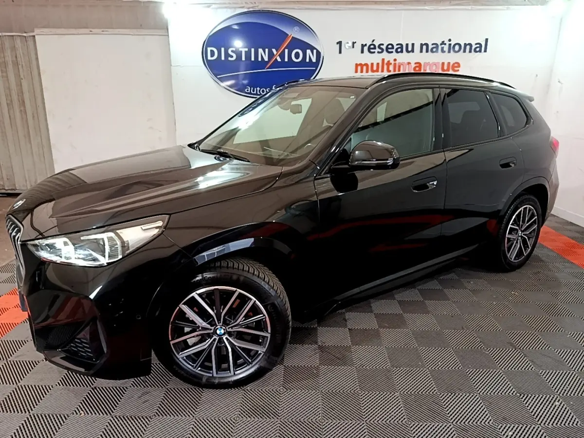 BMW X1 xDrive23i M Sport noir, vue 3/4 avant droit, avec jantes alliage et phares LED ellipsoïdaux visibles.