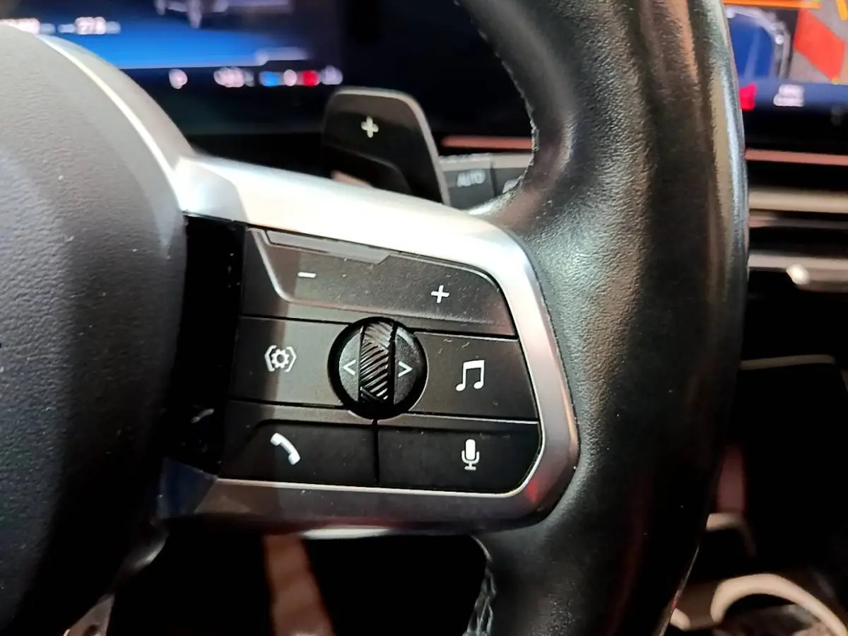 Gros plan sur les commandes multifonctions en cuir noir du volant du BMW X1 xDrive23i M Sport 2023.