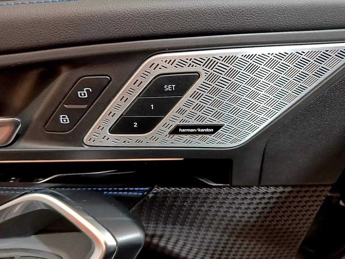 Détail intérieur côté conducteur BMW X1 noir 2023, commandes mémoire siège et haut-parleur Harman Kardon.