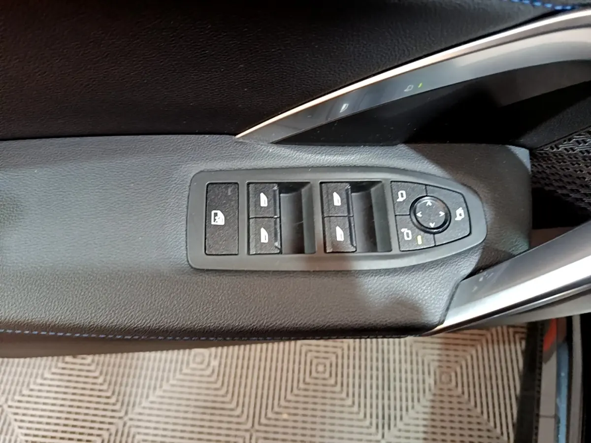 Gros plan sur les commandes de lève-vitres et rétroviseurs côté gauche noir du BMW X1 xDrive23i M Sport 2023.