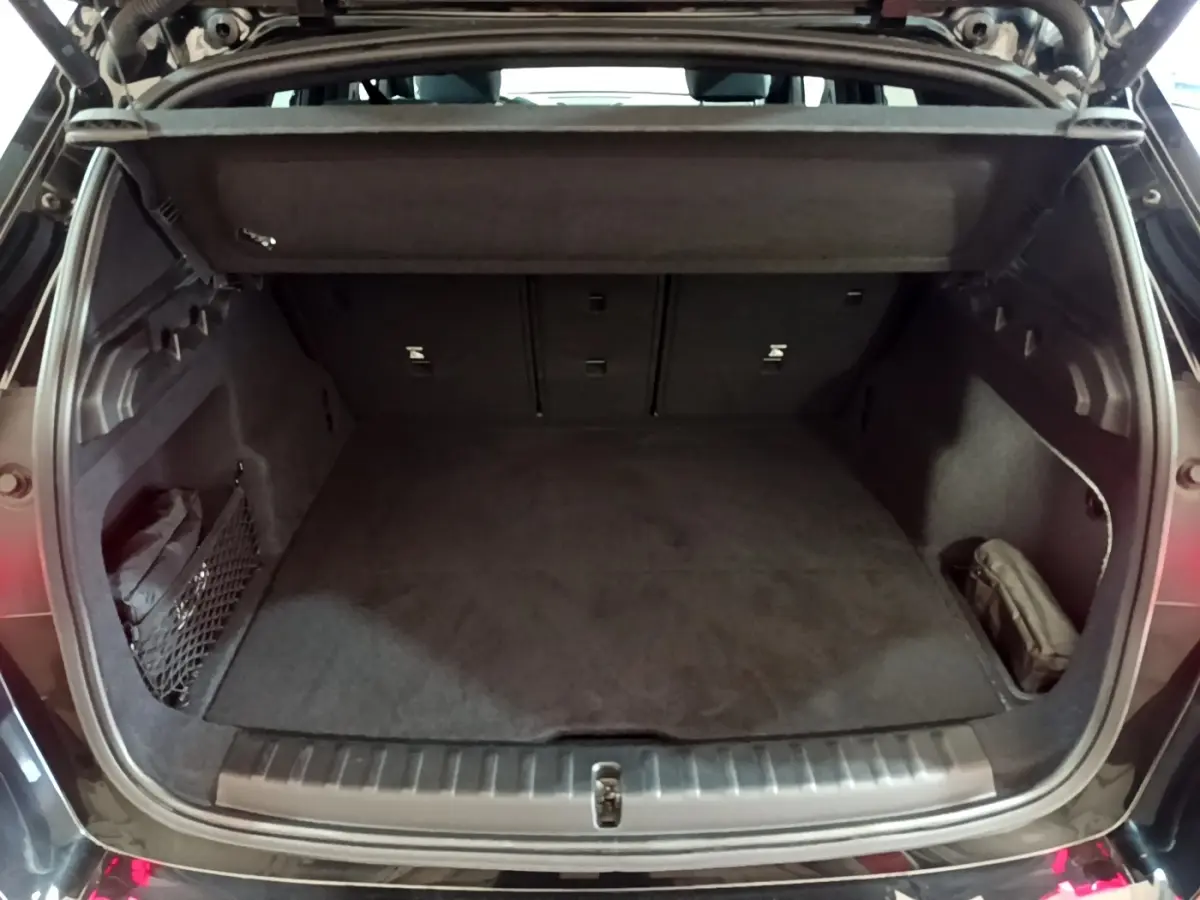 Coffre ouvert vu de l'arrière d'une BMW X1 xDrive23i M Sport noir, montrant un espace de chargement vide et bien fini.