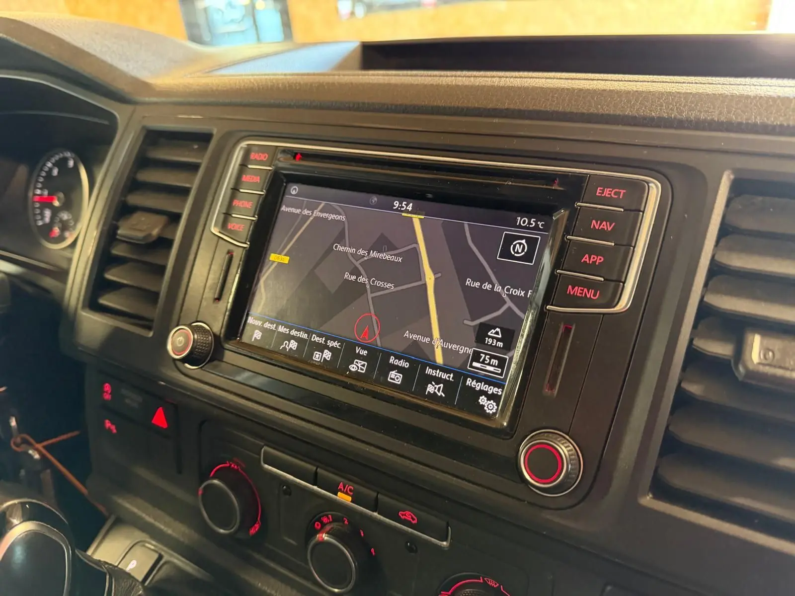 Vue intérieure du tableau de bord du Volkswagen Transporter blanc 2019, mettant en valeur l'écran GPS central et les commandes climatiques.
