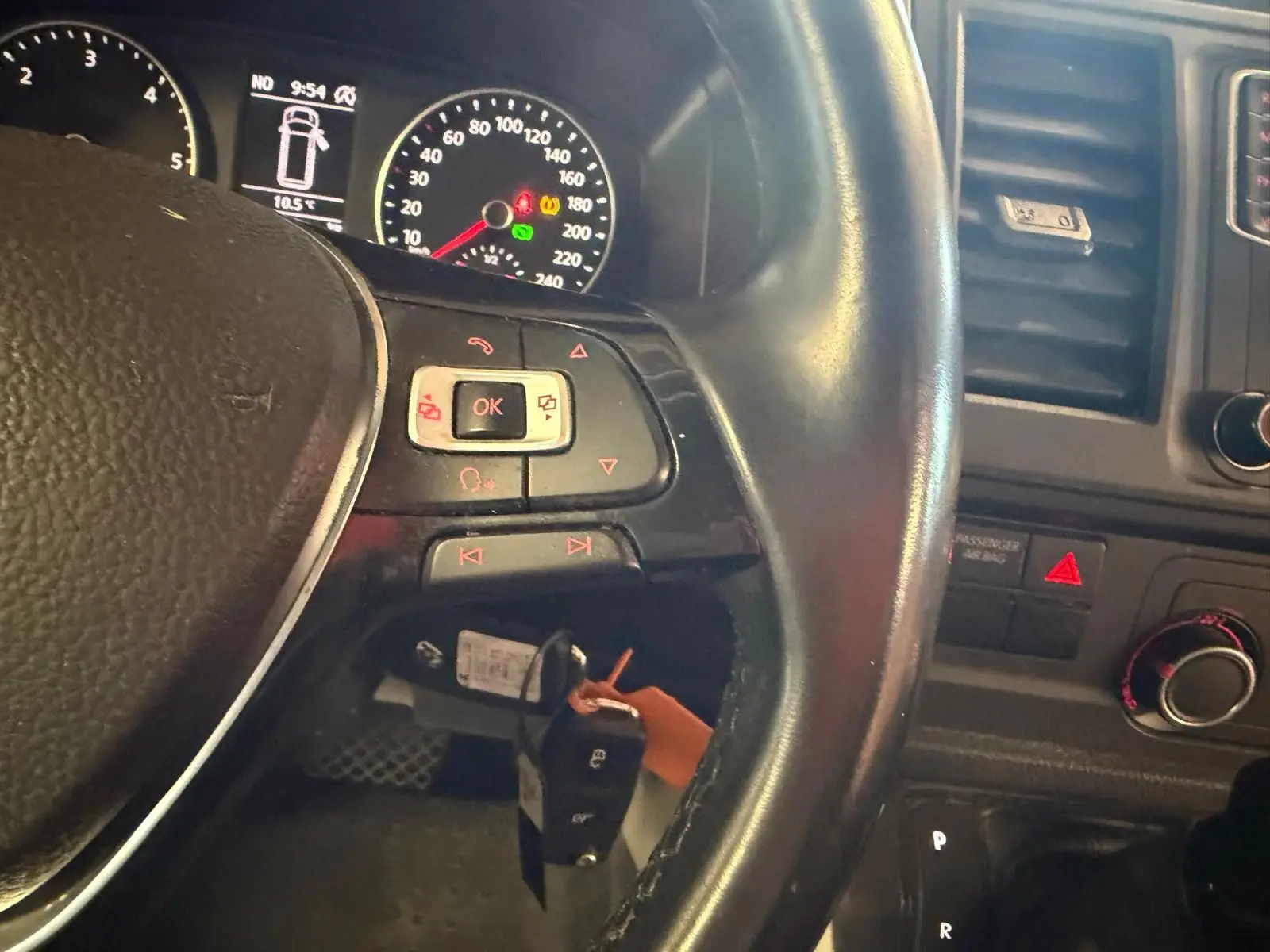 Vue rapprochée du volant noir et du tableau de bord du Volkswagen Transporter blanc, avec clés en contacteur et commandes au volant.