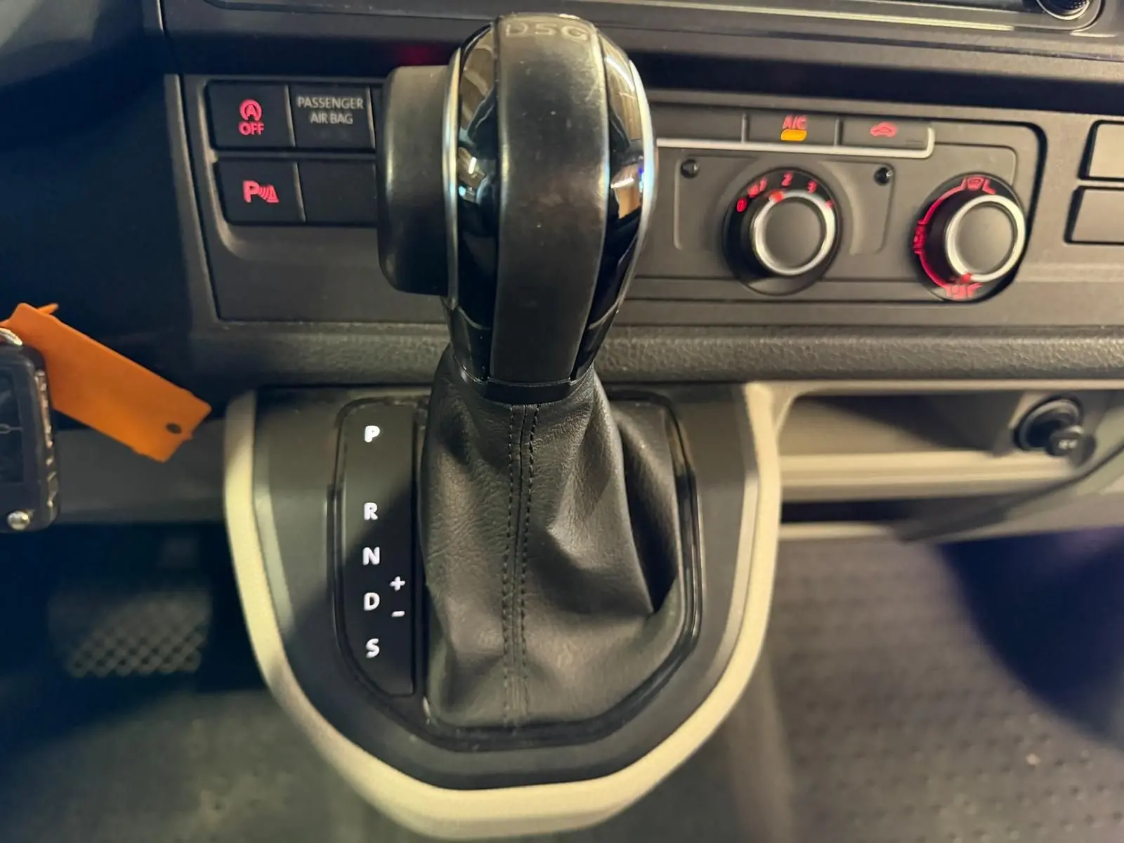 Gros plan sur le levier de vitesse automatique DSG noir du Volkswagen Transporter blanc, avec commandes de climatisation en arrière-plan.