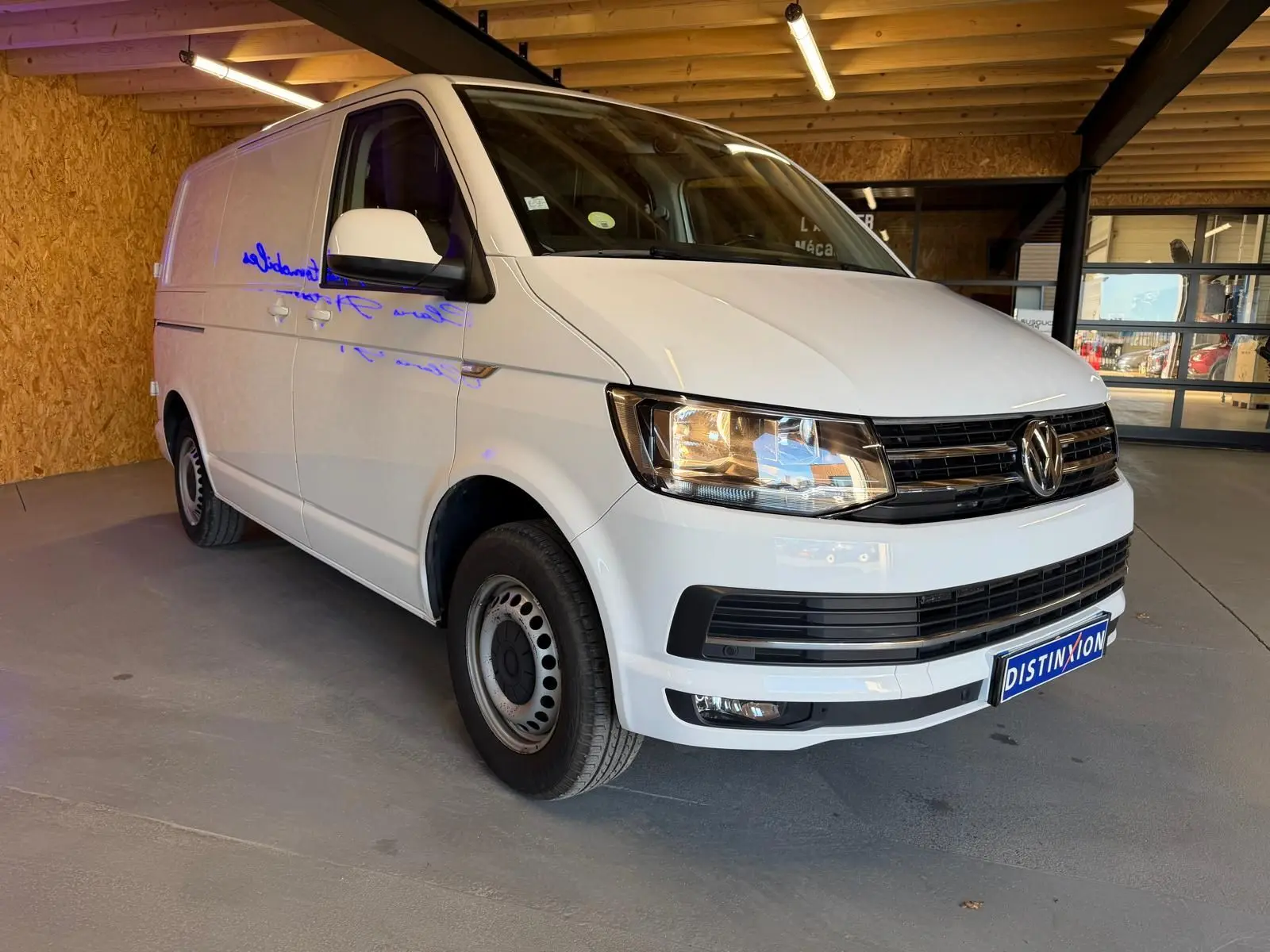 Vue 3/4 avant droit d’un Volkswagen Transporter blanc 2019, utilitaire avec calandre noire et jantes acier.