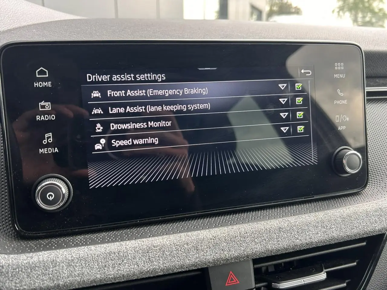 Écran tactile central de la Skoda Scala TSI 116 DSG7 affichant les réglages d’aides à la conduite.
