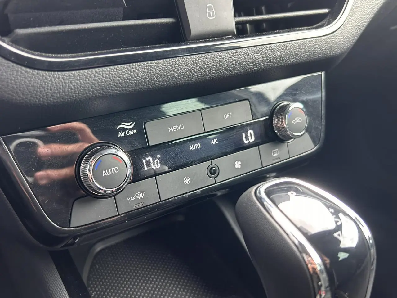 Gros plan sur la console centrale noire du Skoda Scala blanc, montrant la climatisation automatique et le levier de vitesses.