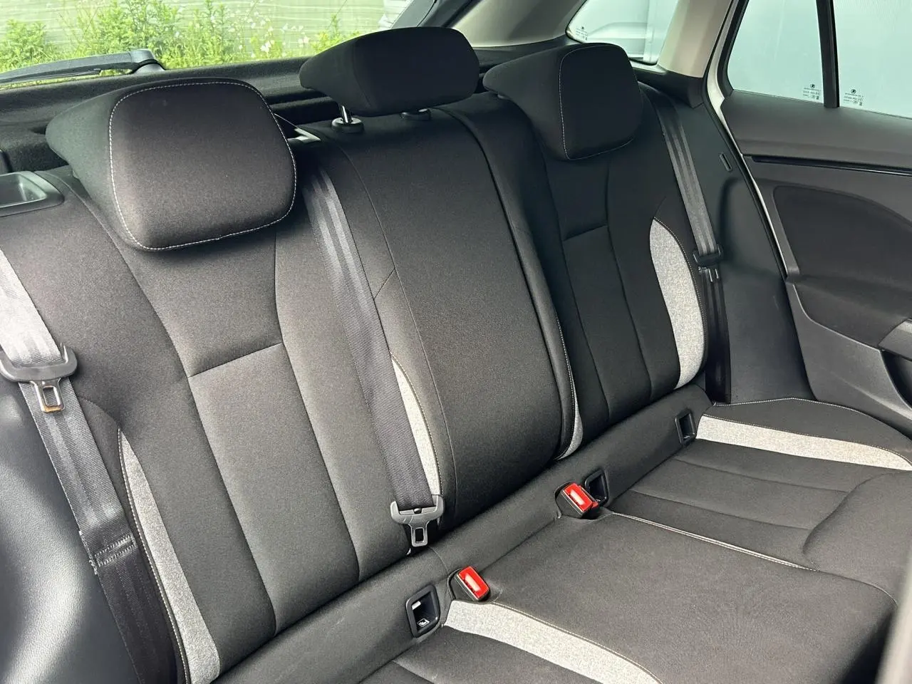 Vue intérieure de la banquette arrière du Skoda Scala 2025, sièges noirs avec surpiqûres grises et ceintures visibles.