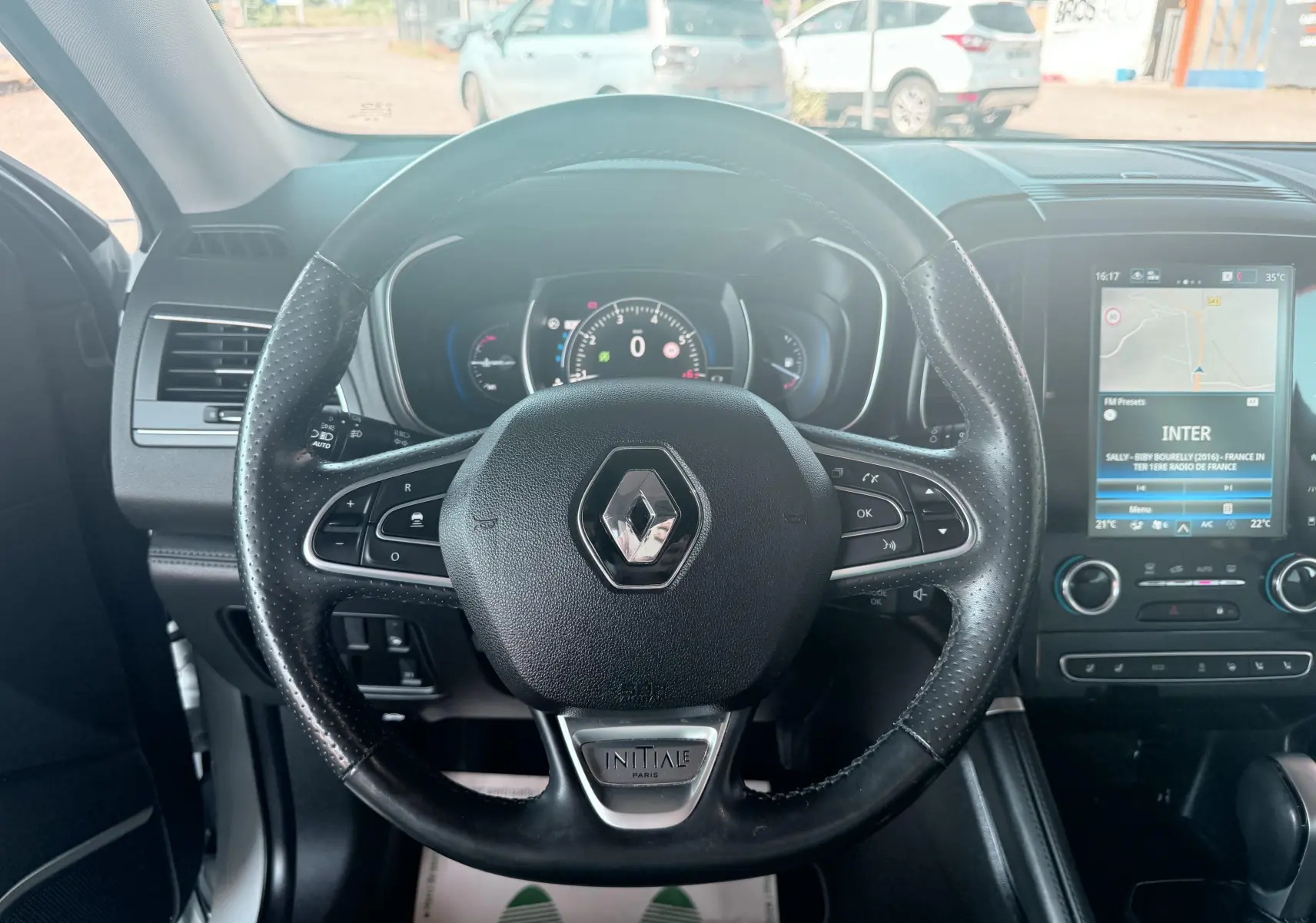 Vue intérieure centrée sur le volant noir perforé avec logo Renault et badge Initiale Paris du Renault Koleos 2021.