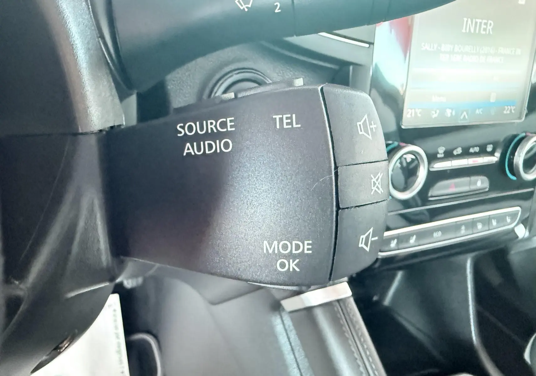 Gros plan sur la commande audio au volant du Renault Koleos 2021, intérieur noir avec tableau de bord et écran tactile.