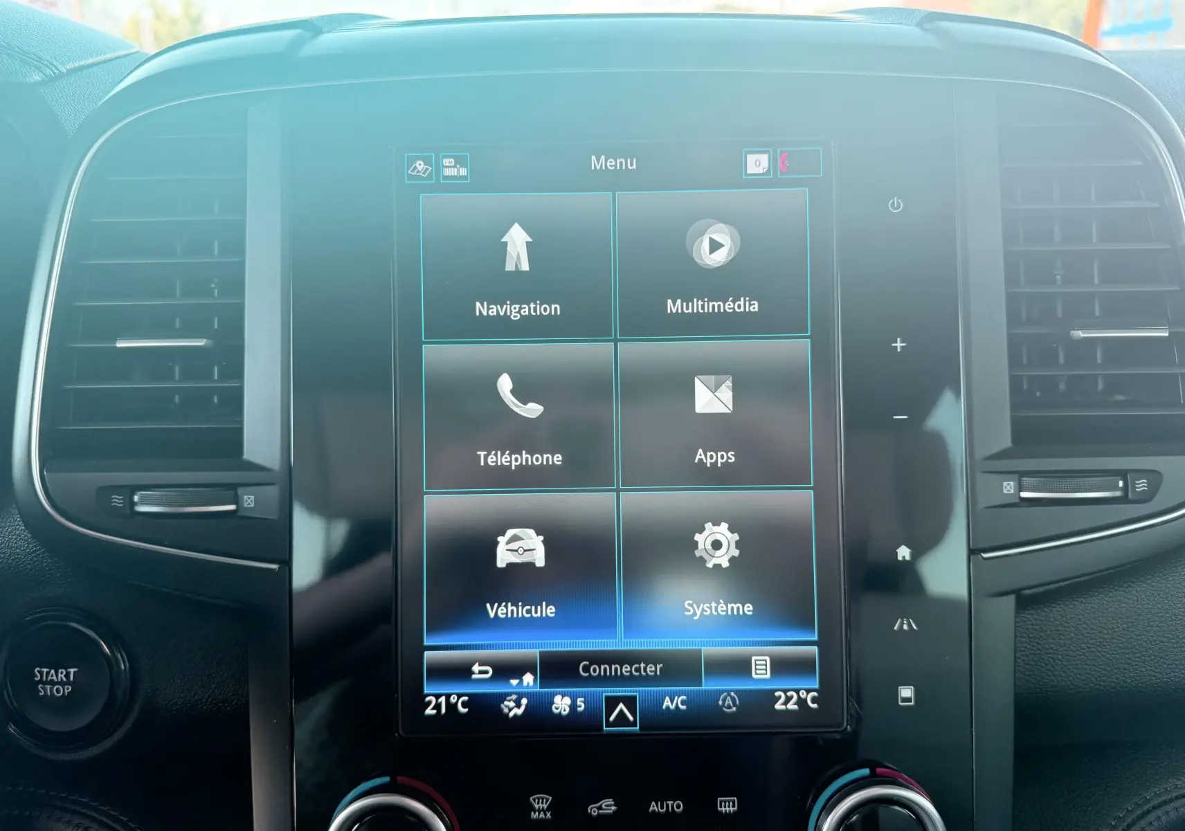 Vue frontale du tableau de bord du Renault Koleos blanc 2021, mettant en valeur l'écran tactile central et les commandes climatiques.