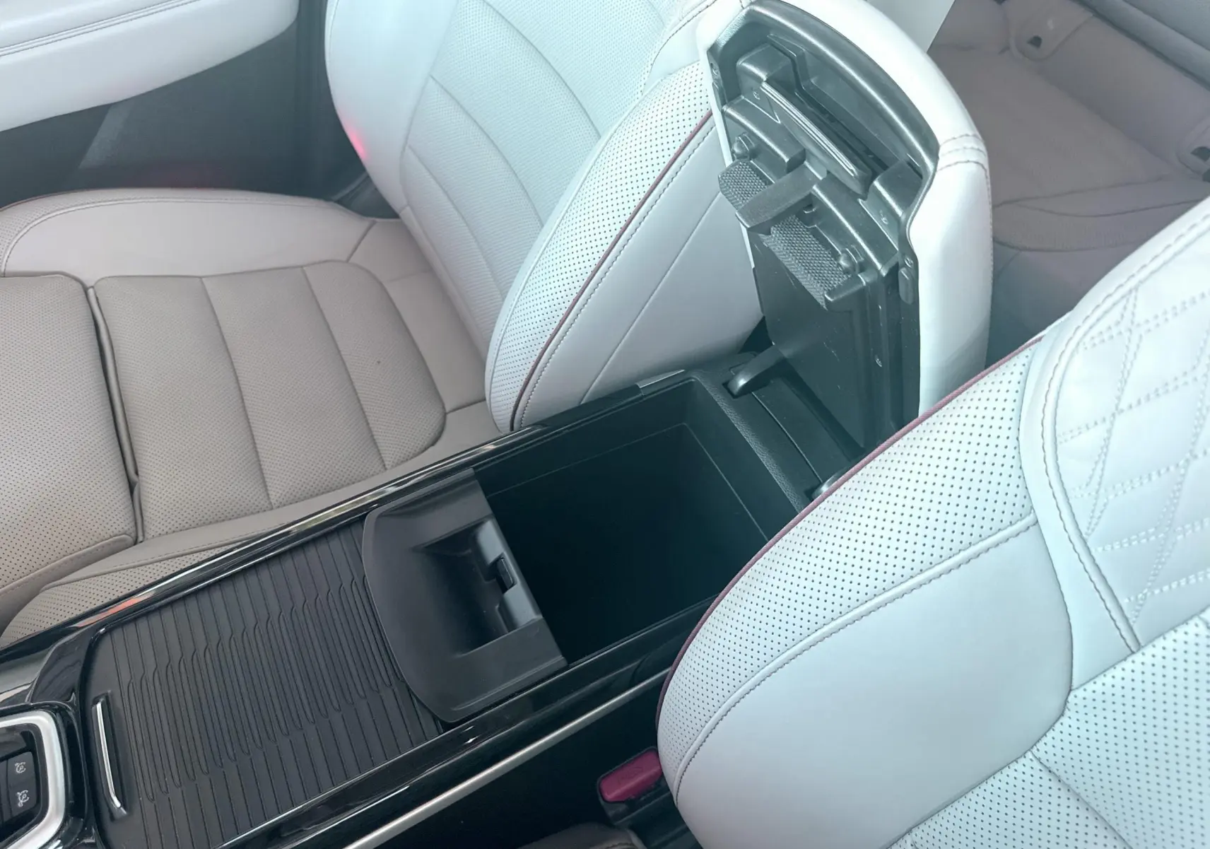 Vue intérieure rapprochée du coffre central ouvert entre les sièges avant en cuir beige clair du Renault Koleos TCE 160.