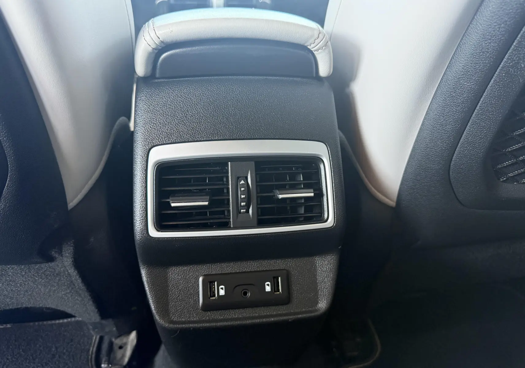 Vue rapprochée de la console centrale arrière noire avec aérateurs et ports USB du Renault Koleos blanc 2021.
