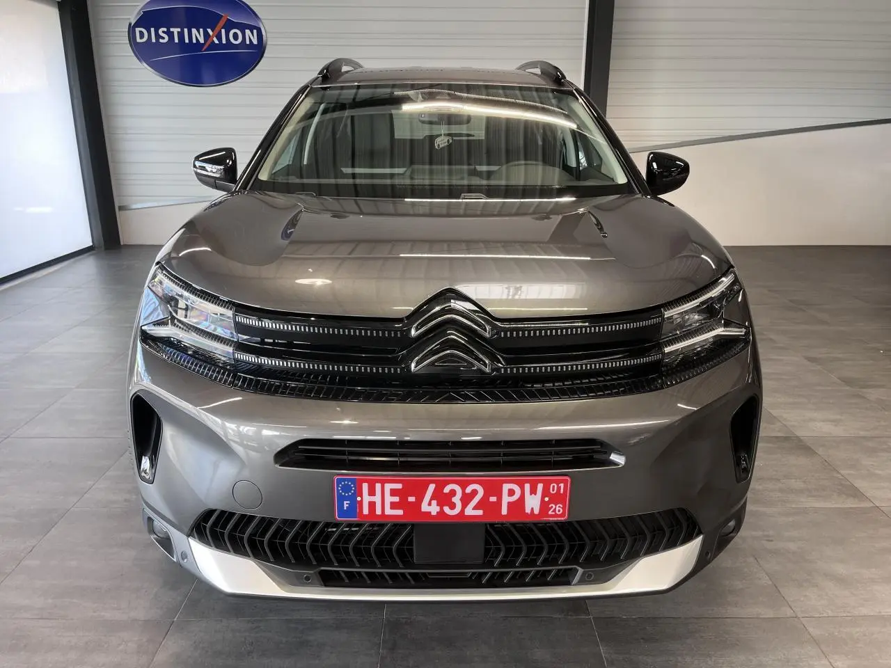 Vue avant d'un Citroën C5 Aircross gris platinium avec calandre noire brillante et plaques d'immatriculation rouges.