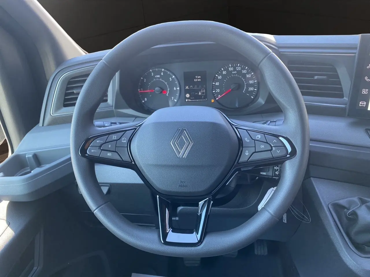 Vue frontale du volant noir du Renault Master 2025 avec commandes intégrées et tableau de bord gris.
