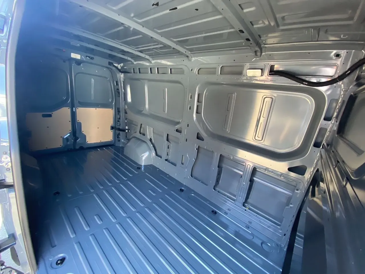 Intérieur de la zone de chargement du Renault Master gris urbain, vue depuis l'arrière avec portes ouvertes.