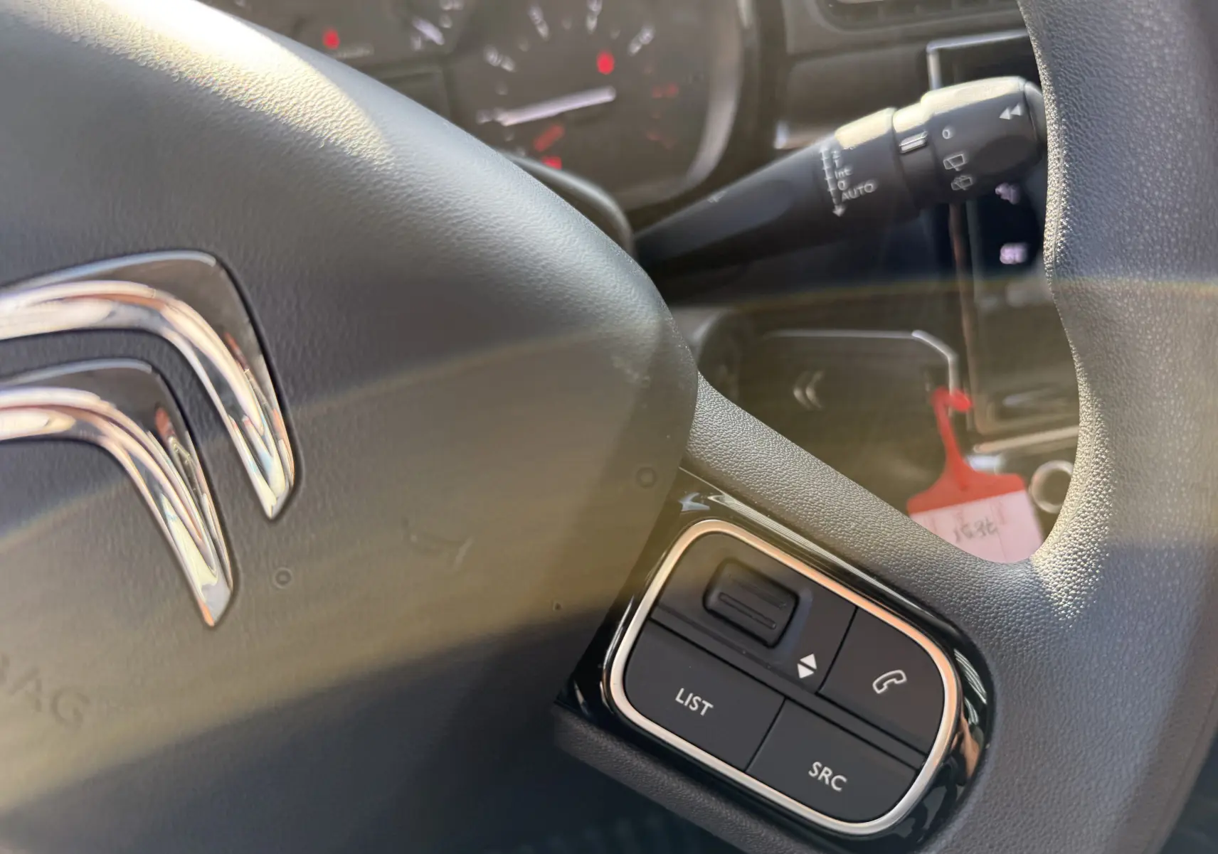 Gros plan sur le volant noir de la Citroën C3 gris acier 2023, avec commandes audio intégrées visibles.