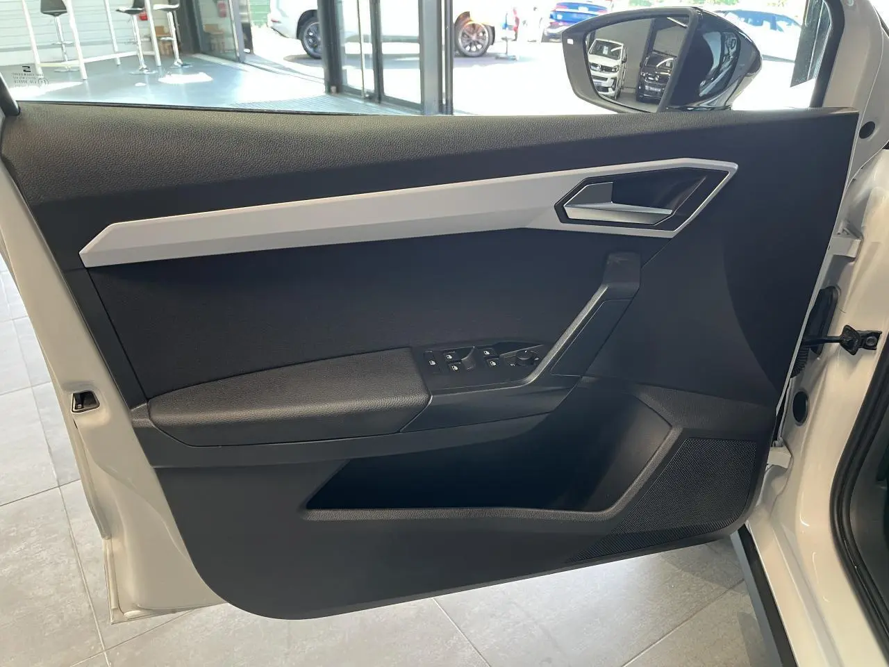 Détail de la porte avant gauche blanche du SEAT Arona 2024 avec commandes de vitres et rétroviseur.