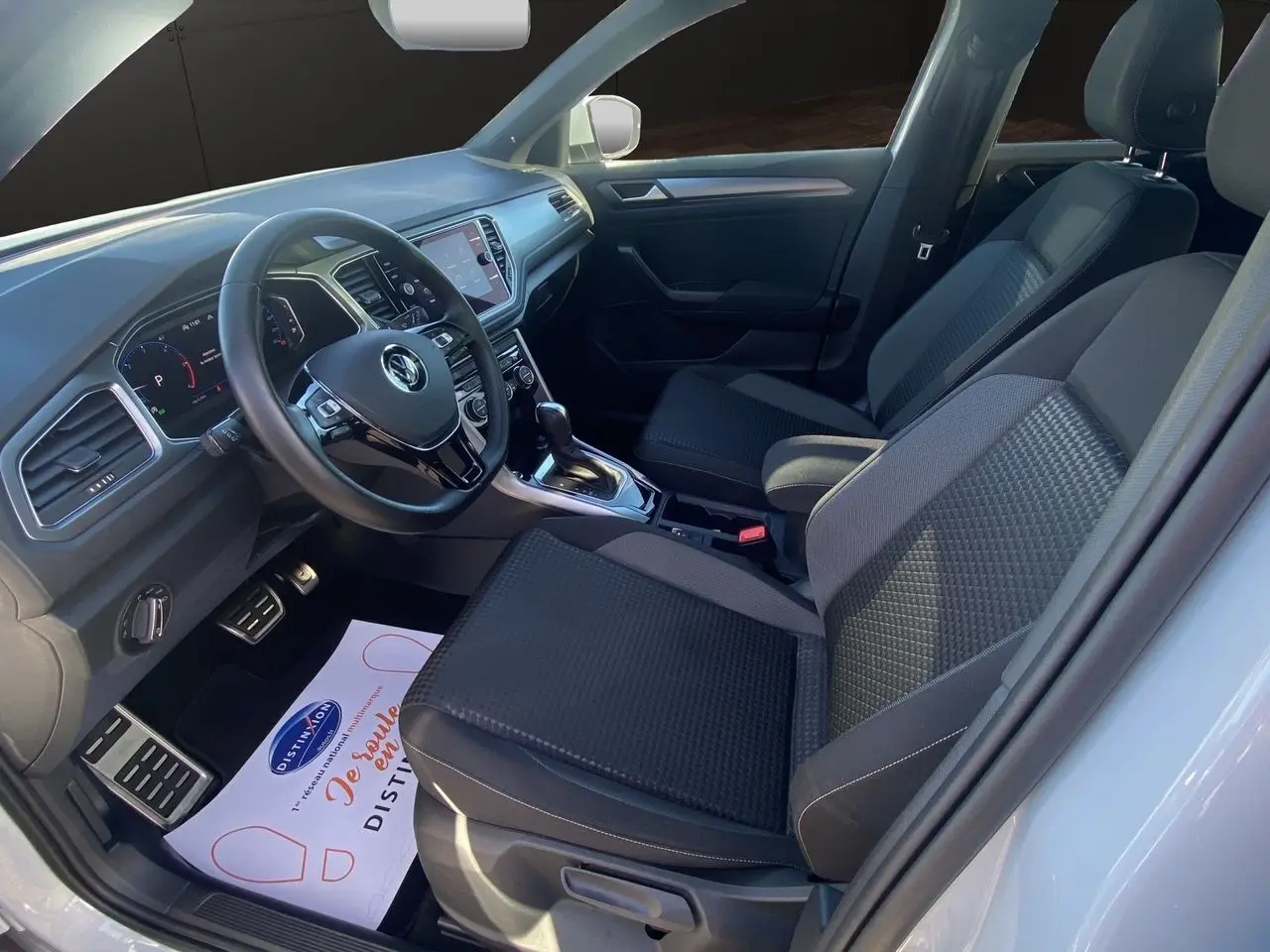 Intérieur du Volkswagen T-Roc 2021 côté conducteur, sièges noirs et tableau de bord moderne avec volant multifonction.