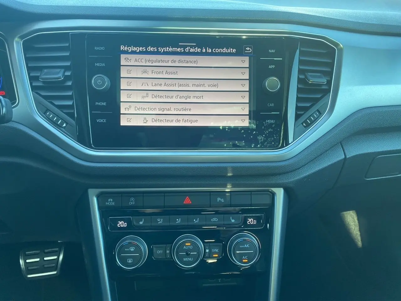 Vue rapprochée de l’écran tactile et de la console centrale du Volkswagen T-Roc 2021 avec affichage des aides à la conduite.