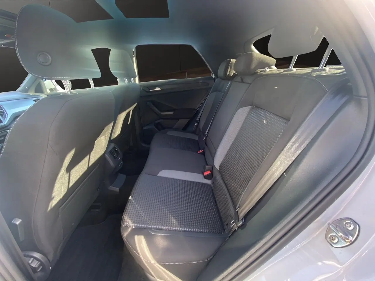 Vue intérieure arrière droite du Volkswagen T-Roc 2021 avec sièges tissu noir et toit ouvrant panoramique visible.