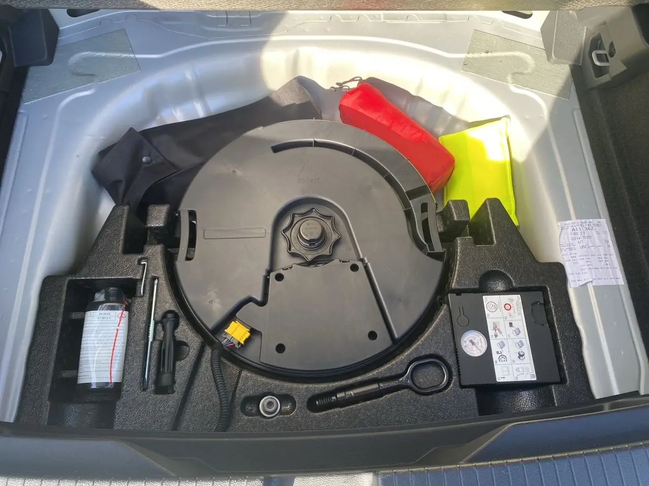 Coffre ouvert du Volkswagen T-Roc 2021 silver white montrant la roue de secours et les outils de bord.