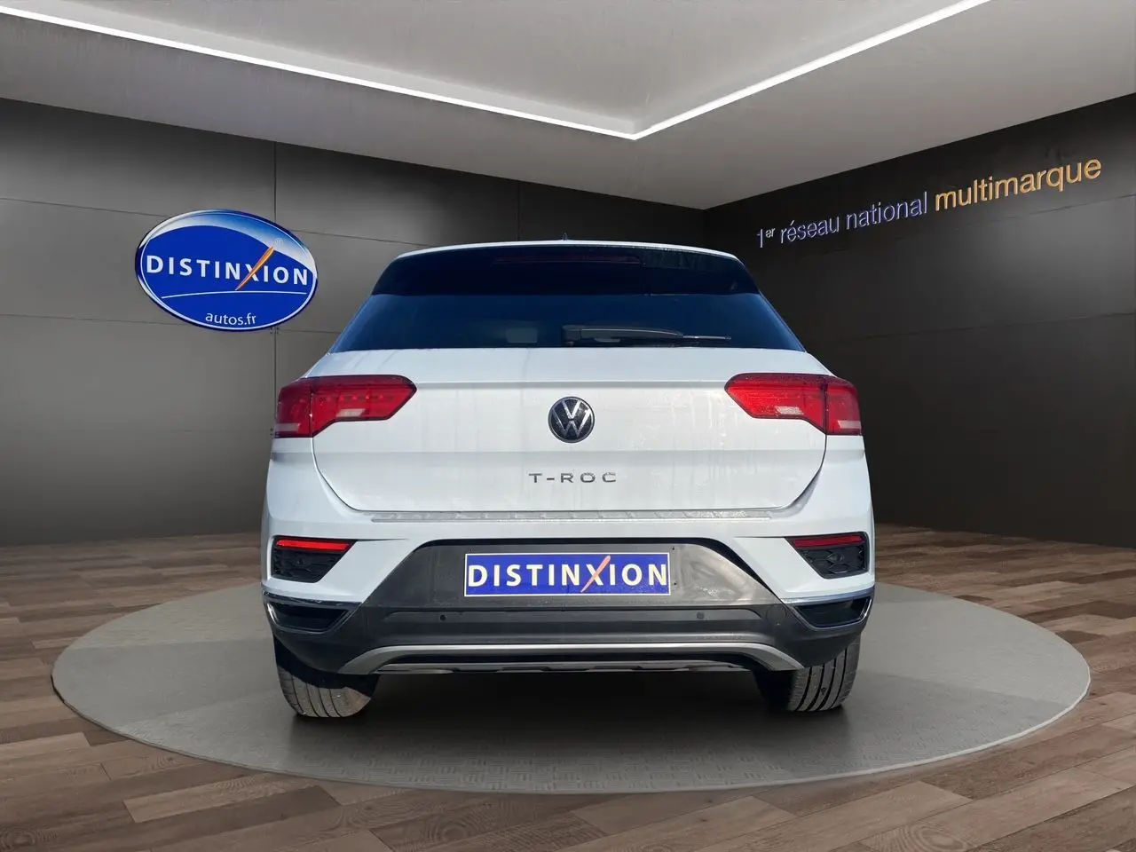 Vue arrière d'un Volkswagen T-Roc blanc argenté 2021 avec hayon motorisé et logo Distinxion visible.