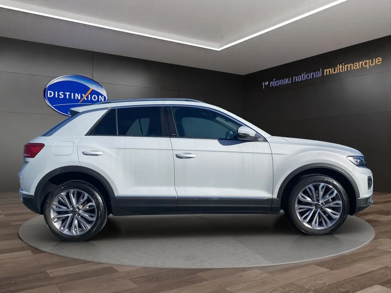 Profil droit d'un Volkswagen T-Roc 2021 blanc argenté avec jantes alu 18 pouces et toit ouvrant panoramique visible.