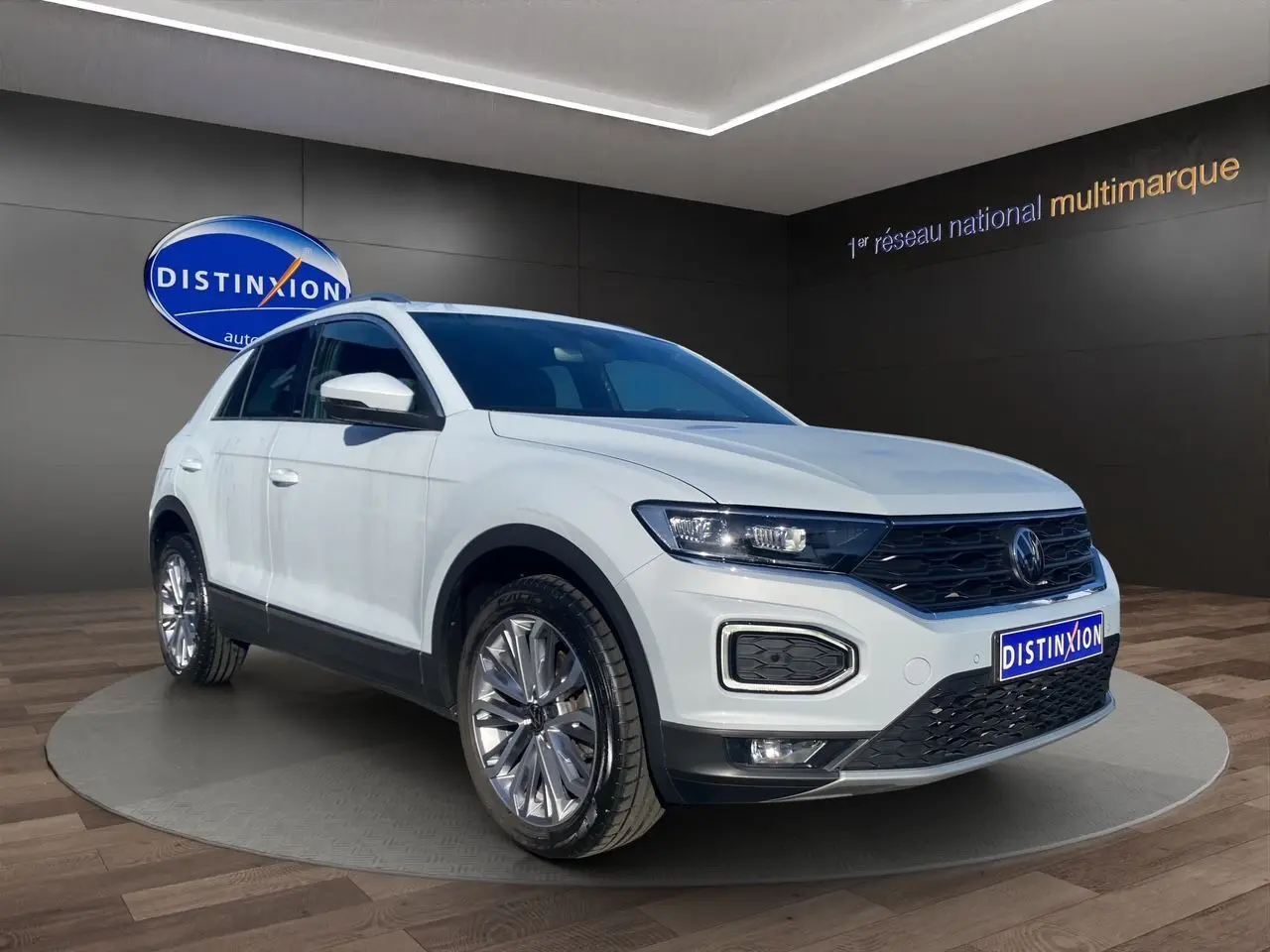 Volkswagen T-Roc Silver White en 3/4 avant droit, avec jantes alu 18 pouces et toit ouvrant panoramique visible.