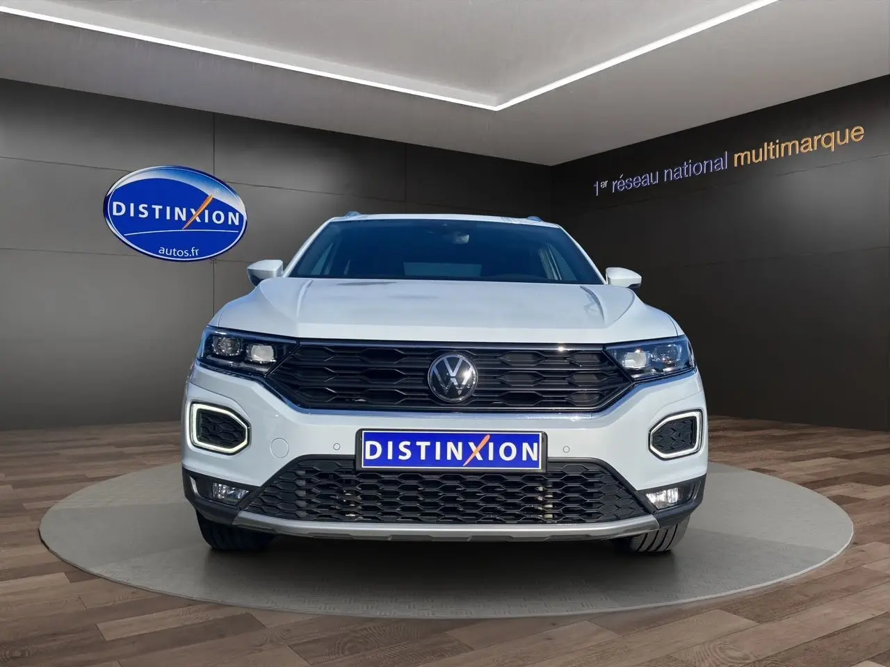 Vue frontale d'un Volkswagen T-Roc 2.0 TDI blanc argenté avec calandre noire et feux LED distinctifs.