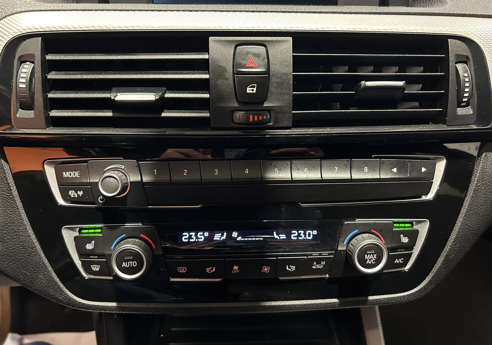 Tableau de bord de BMW Série 1 120iA 2019 montrant la console centrale avec commandes climatisation et sièges chauffants activés.