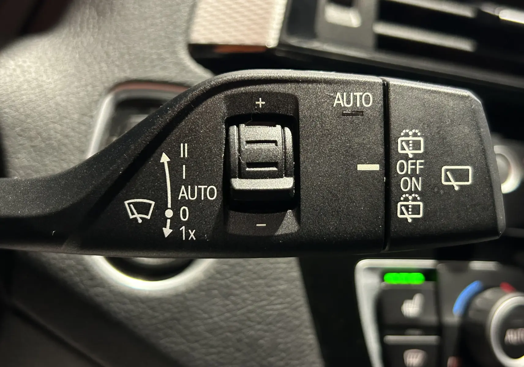 Gros plan sur la commande de l'essuie-glace automatique dans l'habitacle d'une BMW Série 1 blanche 120iA M Sport 2019.