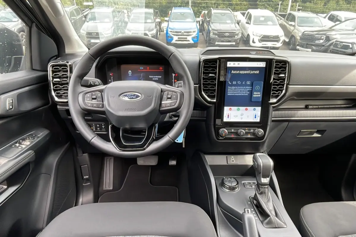 Vue intérieure du Ford Ranger 2025 gris iconic, tableau de bord moderne avec écran tactile vertical et volant multifonction.