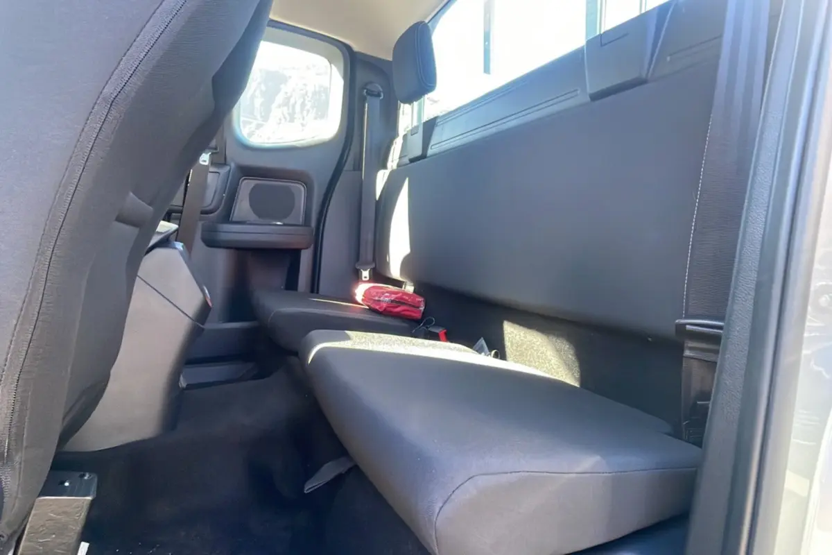 Vue intérieure arrière côté droit du Ford Ranger 2025 gris iconic, montrant la banquette et un kit de secours rouge posé dessus.