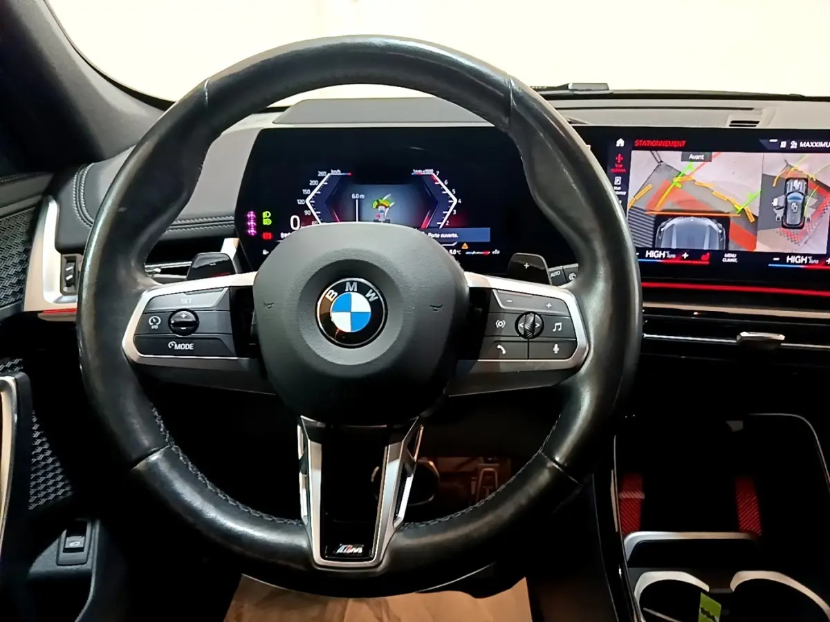 Vue frontale du volant cuir noir BMW X1 xDrive23i M Sport 2023 avec tableau de bord digital et écran tactile de navigation.