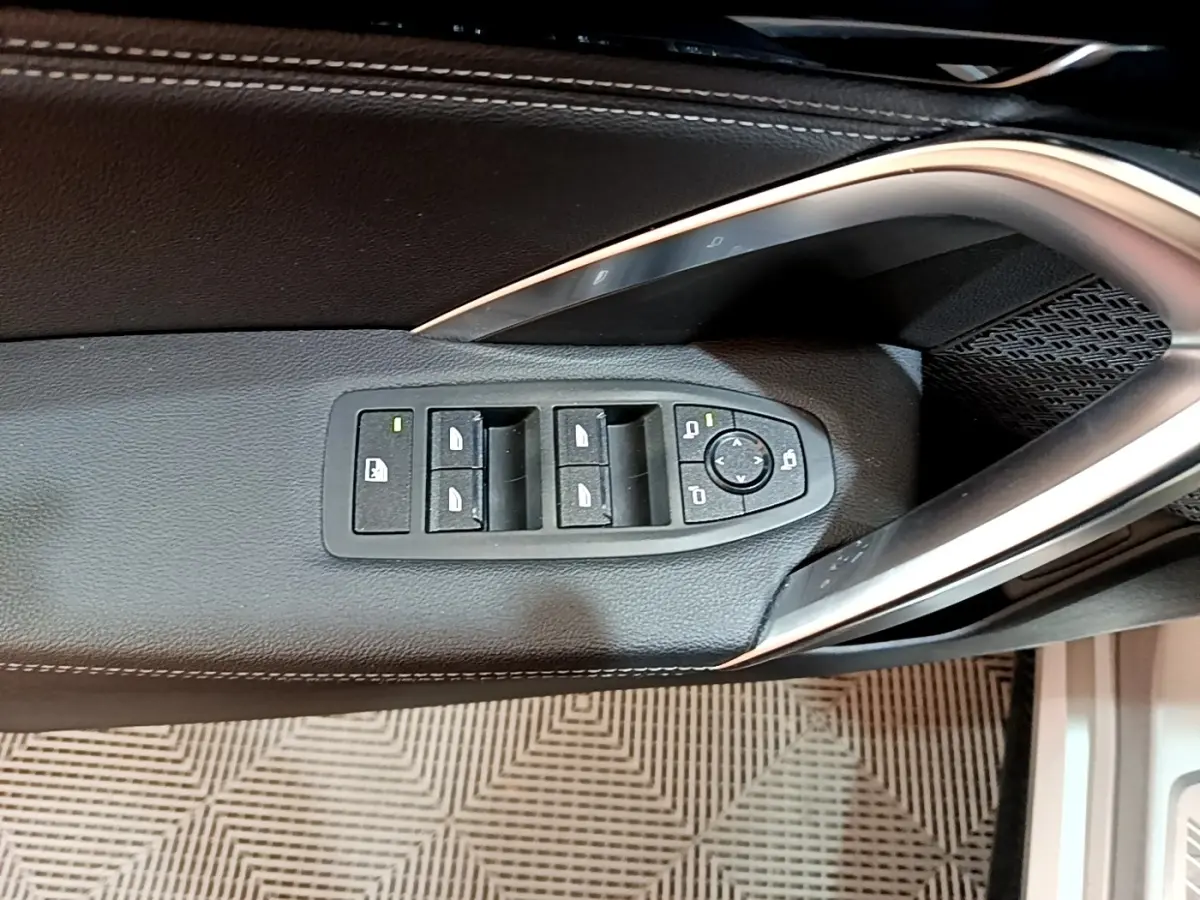 Commande des vitres et rétroviseurs sur la porte côté conducteur d’un BMW X1 gris clair xDrive23i M Sport 2023.