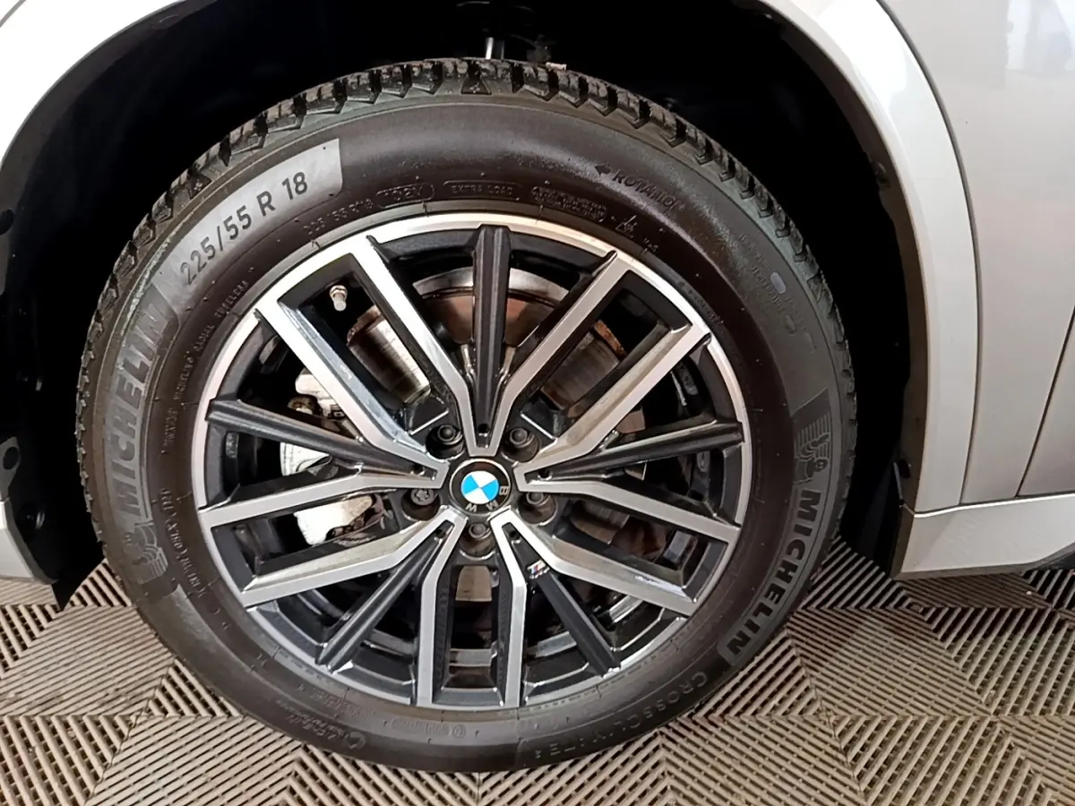 Gros plan sur la roue avant droite gris clair du BMW X1 xDrive23i M Sport avec jante alliage noir et argent.