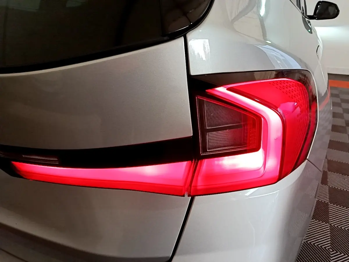Feu arrière droit allumé sur BMW X1 xDrive23i M Sport gris clair, vue rapprochée du coin arrière du véhicule.