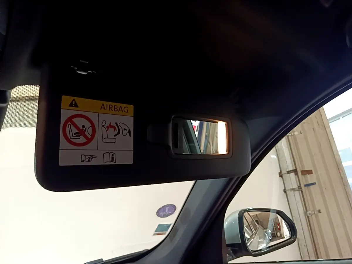 Vue intérieure côté conducteur du pare-soleil avec miroir éclairé et rétroviseur extérieur gris clair d’un BMW X1 2023.