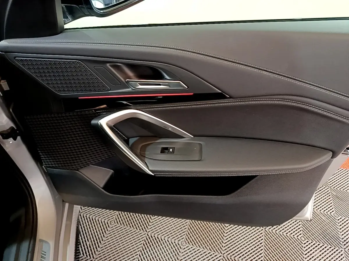 Vue intérieure côté gauche de la porte avant gris clair du BMW X1 xDrive23i M Sport avec garniture noire et insert chromé.