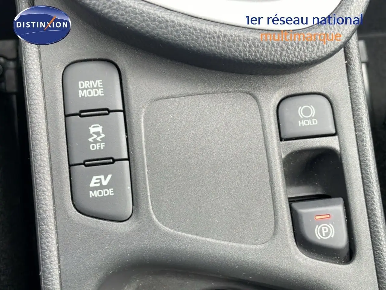 Gros plan sur la console centrale noire de la Toyota Yaris Cross 2024, montrant les boutons Drive Mode, EV Mode et frein à main électronique.