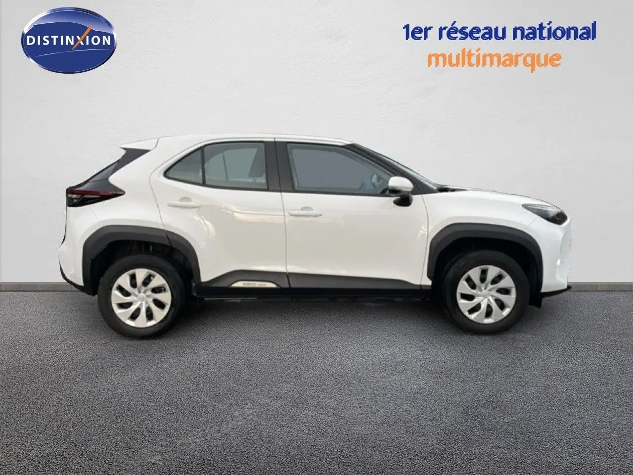 Profil côté droit de la Toyota Yaris Cross 2024 blanche, soulignant ses lignes modernes et ses protections noires contrastantes.