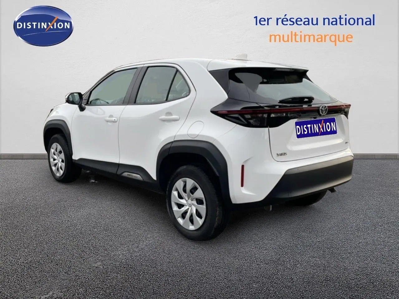 Toyota Yaris Cross blanc pur en 3/4 arrière droit, avec protections noires et feux arrière étirés.