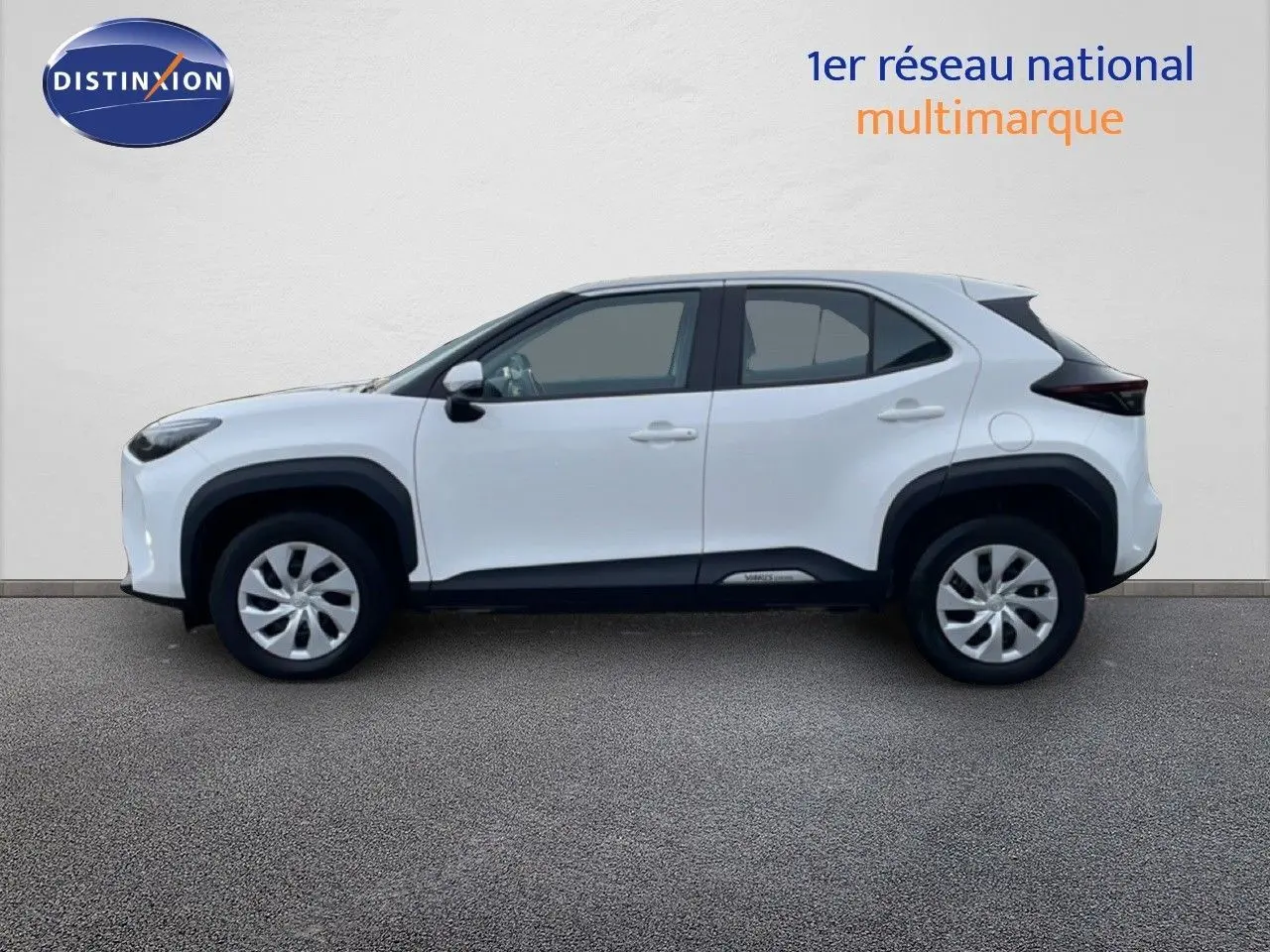 Vue de profil côté gauche d'une Toyota Yaris Cross blanche pure, version hybride 2024 avec protections noires sur les passages de roues.