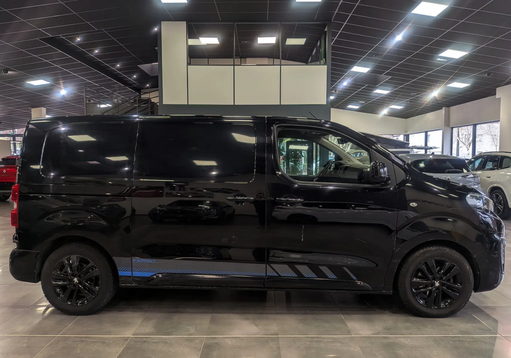 Profil droit du Peugeot Expert Fourgon noir Perla avec jantes noires et bandeau bleu Sport visible en bas de caisse.
