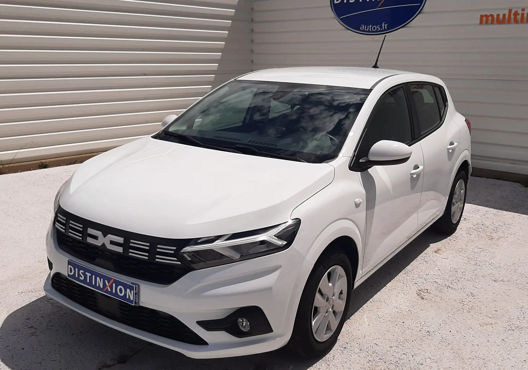 Vue 3/4 avant droite d'une Dacia Sandero TCE 90ch Expression blanche Glacier, avec calandre noire et feux LED distinctifs.