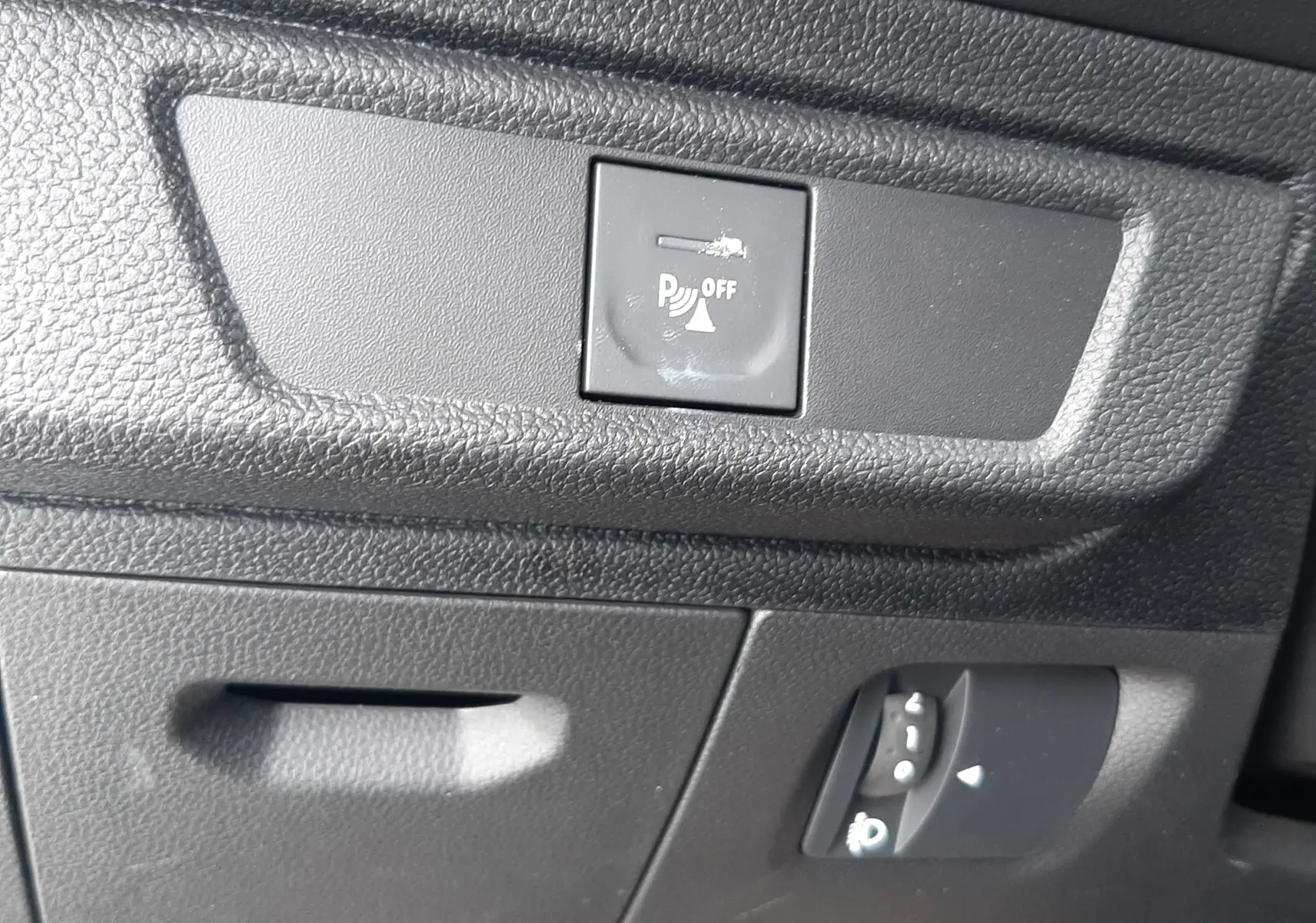 Gros plan sur le tableau de bord noir de la Dacia Sandero 2024, montrant le bouton de désactivation du radar de recul.