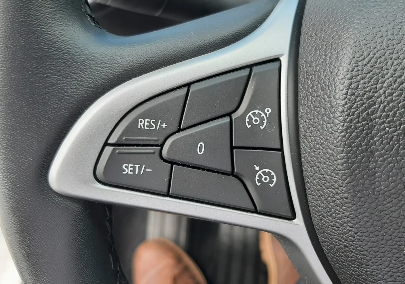 Gros plan sur les commandes de régulateur de vitesse au volant noir d'une Dacia Sandero blanche Glacier 2024.