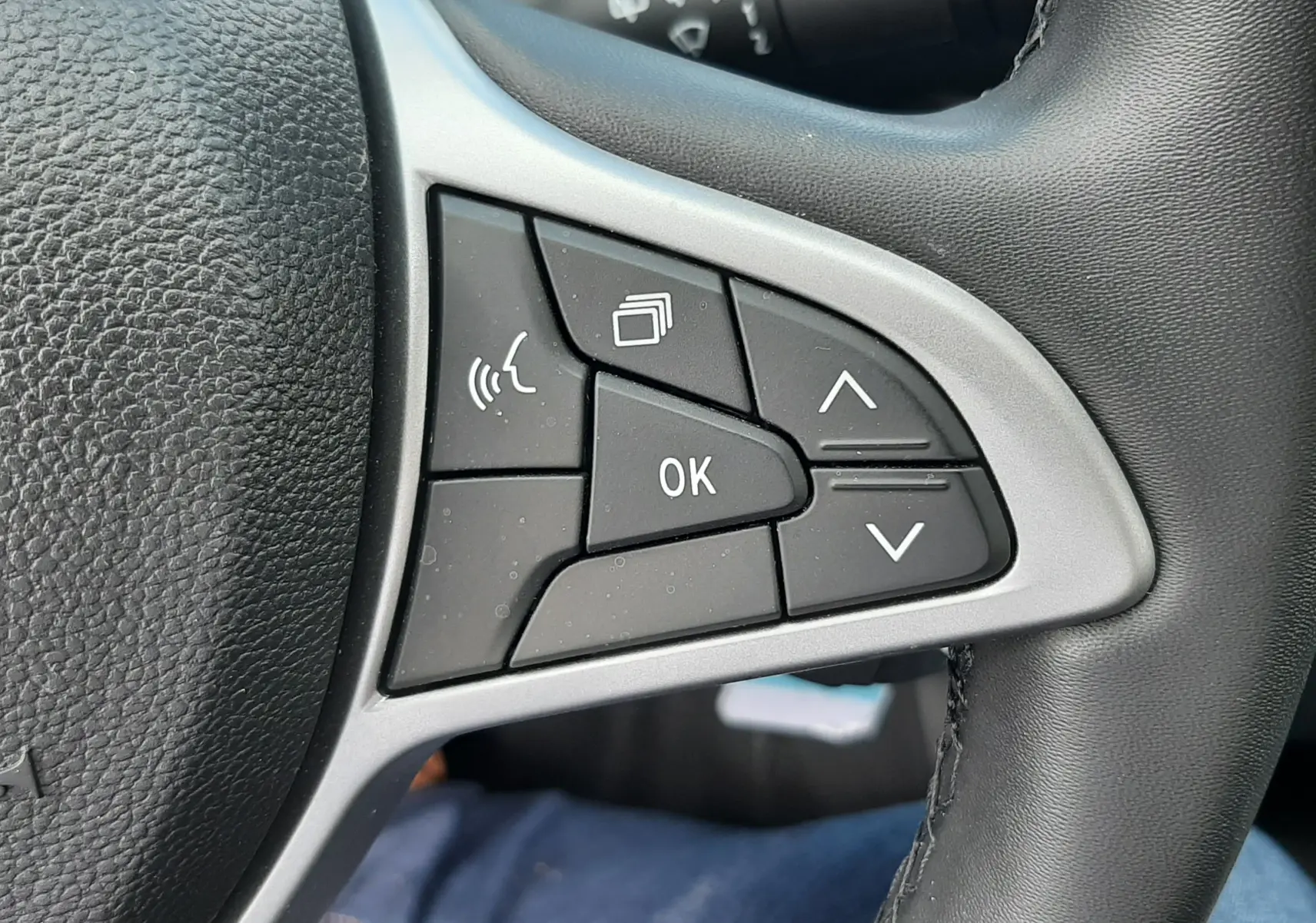 Gros plan sur les commandes multifonctions côté gauche du volant noir de la Dacia Sandero TCE 90ch Expression 2024.