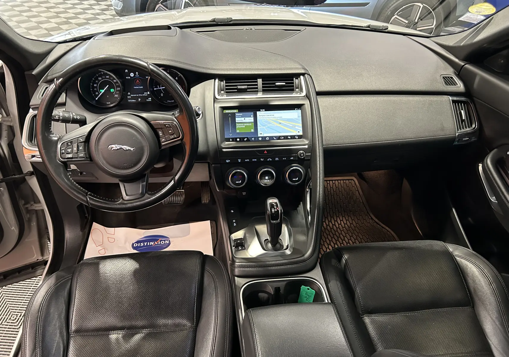 Vue intérieure avant du Jaguar E-PACE 2018 avec tableau de bord noir, volant cuir et écran tactile central allumé.